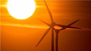 Die Sonne geht hinter Windrädern auf.