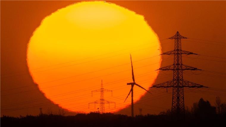 Die Sonne geht hinter Windrädern und Hochspannungsleitungen in der Region Hannover auf.