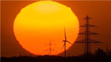Die Sonne geht hinter Windrädern und Hochspannungsleitungen in der Region Hannover auf.