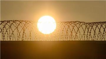 Die Sonne geht über der drahtbewährten Mauer der Justizvollzugsanstalt Burg auf.