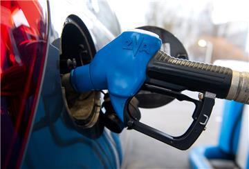 Eine Zapfpistole steckt an einer Tankstelle in der Tanköffnung eines Fahrzeugs.