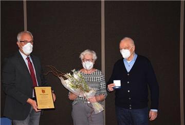 Zevens Bürgermeister Norbert Wolf steht mit Ilona und Ferdinand Rogge auf der Bühne des Ratshaussaals in Zeven.
