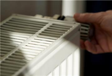 Eine Frau dreht an einem Heizungsthermostat.