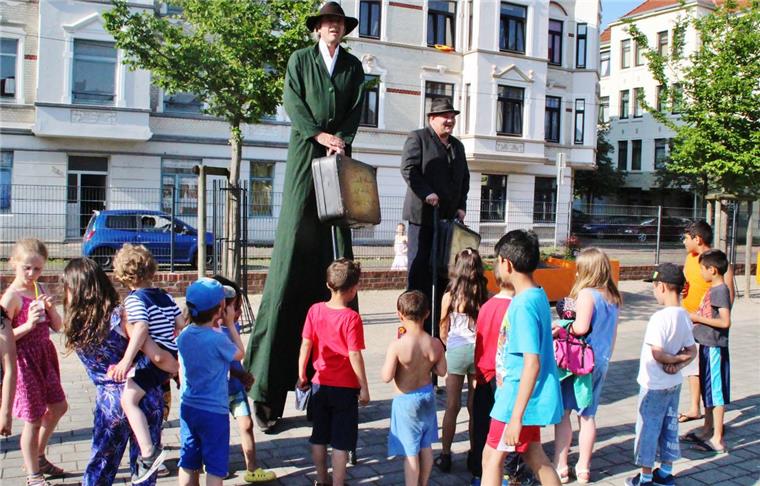 Die Stelzenläufer werden auf dem Leher Pausenplatz bei ihrem Marsch zur Theo sofort von Kindern umringt.