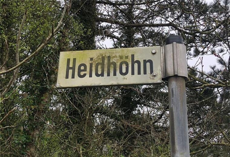 Ein Straßenschild mit der Beschriftung "Heidhöhn" vor einigen Bäumen