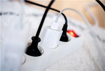 Die Netzstecker mehrerer Elektrogeräte stecken in einer Steckdosenleiste in einem Wohnzimmer. 