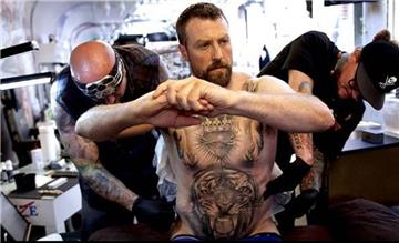 Die Tattoo-Künstler bearbeiten den Rücken von Andrew McPherson.