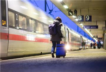 Eine Frau geht mit einem Koffer neben einem ICE im Hauptbahnhof Hannover.