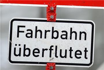 Ein Verkehrsschild warnt vor einer überfluteten Straße.