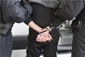Zwei Polizisten führen einen Mann in Handschellen ab.