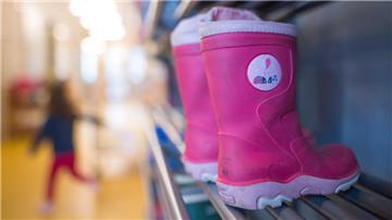 Blick in eine Kita. Lilafarbene Stiefel sind rechts zu sehen, links unscharf ein Kind. Die von der Gewerkschaft Verdi angekündigten Warnstreiks am Freitag könnten zu deutlichen Einschränkungen, besonders in den Kitas in Bremerhaven und dem Cuxland, führen.