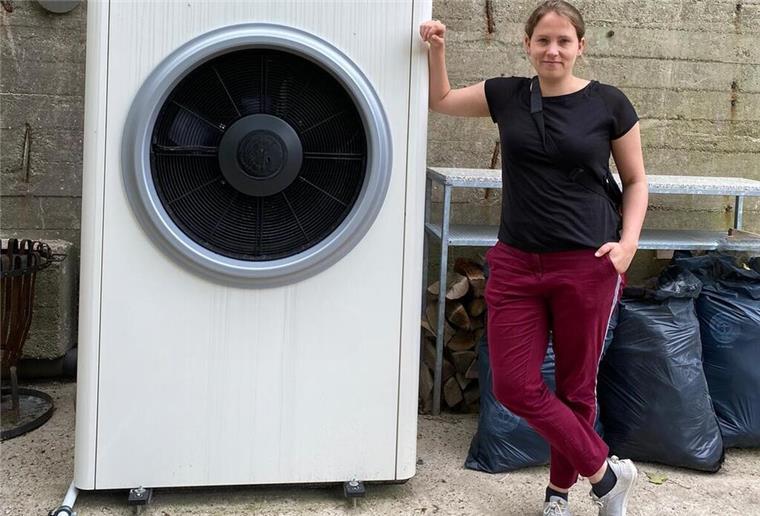 Eine Frau lehnt an einer großen Wärmepumpe