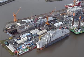 Die Westkaje im Kaiserhafen mit verhülltem Schiff im Dock und einem Offshore-Errichterschiff. Später wird hier das große Schwimmdock der Werft unterkommen.