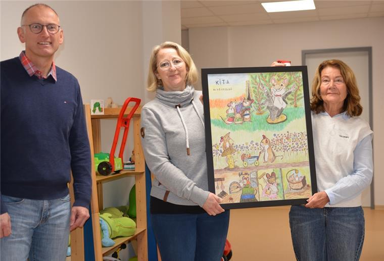 Zwei Frauen halten ein Bild in die Höhe, ein Mann steht links daneben.