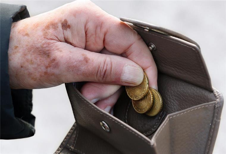 Eine Frau am holt Münzen aus ihrem Portemonnaie.