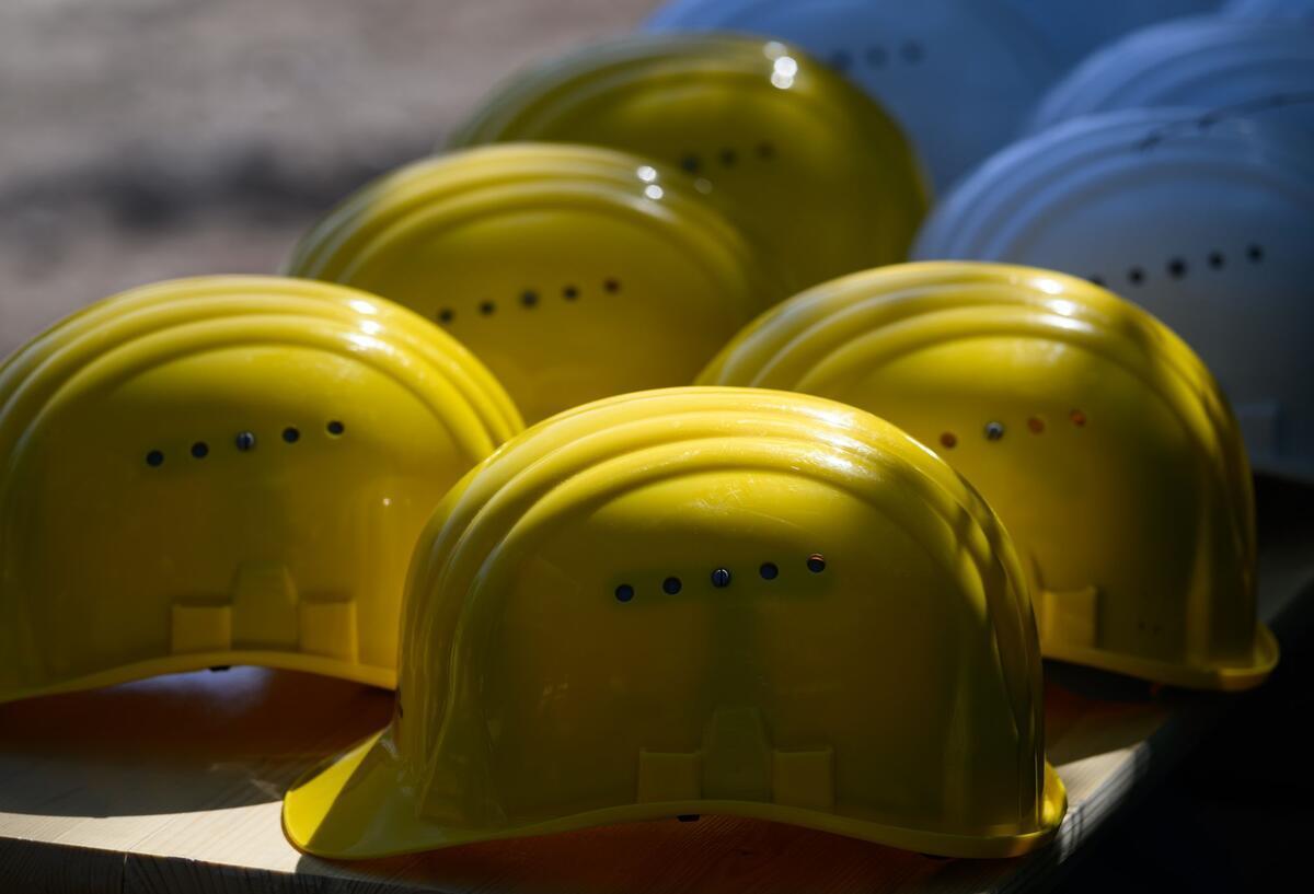 Krise in der Zeitarbeitsbranche: So schlimm ist das Ausmaß wirklich Mehrere gelbe Schutzhelme liegen auf einer Bank.