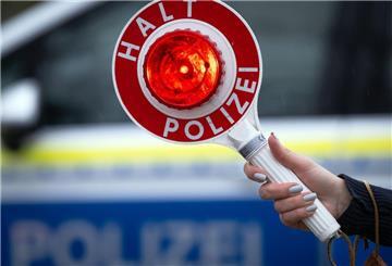 Ein Polizist hält eine Polizeikelle für eine Kontrolle an der Autobahn.