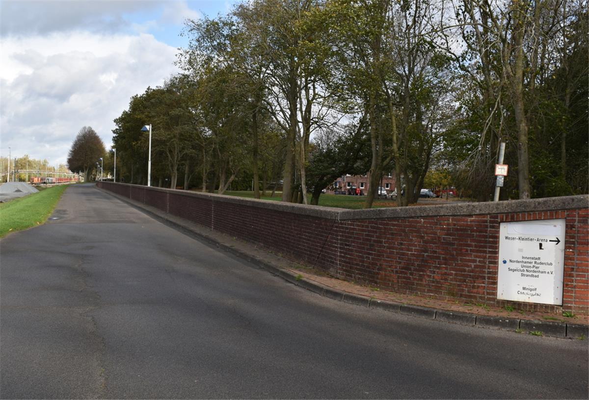 Nordenham: Fahrradstraße parallel zum Strand wäre möglich Neben einer leeren Straße ist links ein Grünstreifen und rechts eine Steinmauer zu sehen.