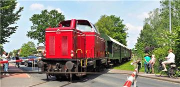 Dieses Bild gibt es in der Langener Ortsmitte nicht so oft zu sehen:
Eine Diesellok überquert den Bahnübergang, bestaunt von Autofahrern
 und Fußgängern. 