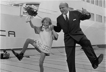 Schauspielerin Inger Nilsson als Pippi Langstrumpf tanzt mit Blumenstrauß in der Hand lachend neben Reeder Sten A. Olsson vor der „Stena Danica“, Sommer 1969.