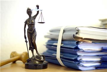 Die modellhafte Nachbildung der Justitia steht im Raum eines Richters des Landgerichts neben einem Holzhammer und einem Aktenstapel.