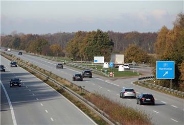Autos fahren auf einer Autobahn. Ein Schild weist auf den Parkplatz „Harmonie“ an der A 27 hin.