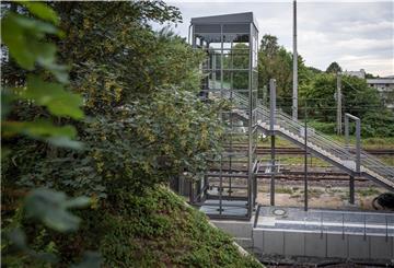 Direkt neben der Treppe zum Bahnsteig des Wulsdorfer Bahnhofs wurde jetzt der gläserne Schacht für den Fahrstuhl aufgestellt. Installiert ist das Innenleben des Aufzuges noch nicht. Erst im November soll die Anlage in Betrieb gehen. Foto: Hartmann