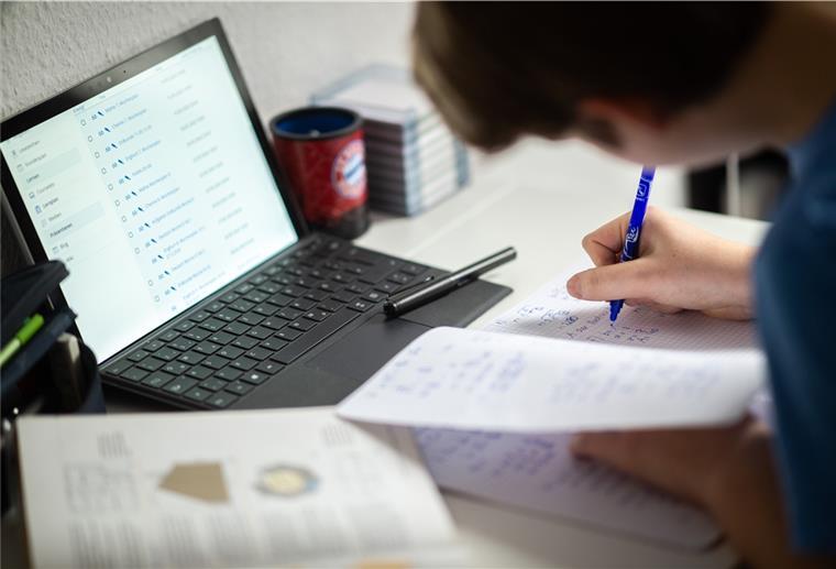 Ein Schüler sitzt in seinem Zimmer am Schreibtisch und erledigt Aufgaben im Rahmen des Homeschooling. 