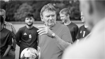 Fußballtrainer Egon Coordes umringt von Spielern.