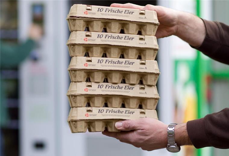 Ein Mann hält mehrere Eierkartons in die Luft. Verkäufer schauen häufig an den Kassen in die Eierkartons, um zu prüfen, dass sich keine kleinen Gegenstände darin befinden. 