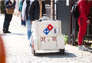 Ein Pizza-Roboter rollt über einen Gehweg.