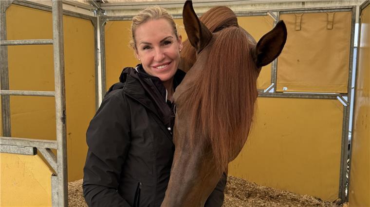 Eine blonde Frau neben einem Pferd.