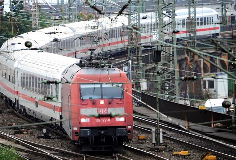 Zug  mit Lokomotive fährt durch Gleisfeld.