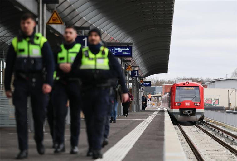 Eine S-Bahn steht an einem Bahnhof. Im Vordergrund laufen Polizisten. 
