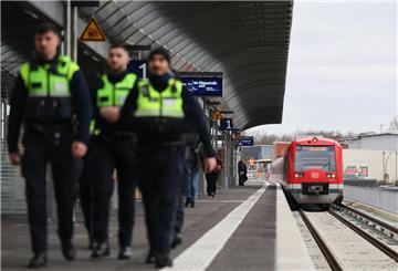 Eine S-Bahn steht an einem Bahnhof. Im Vordergrund laufen Polizisten. 