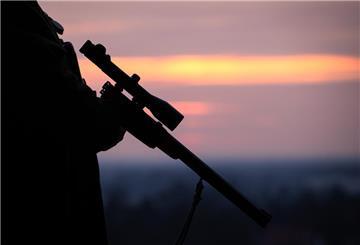 Ein Jäger hält sein Gewehr in der Abenddämmerung.