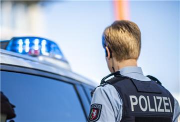 Eine Polizistin steht vor einem Streifenwagen, dessen Blaulicht leuchtet.