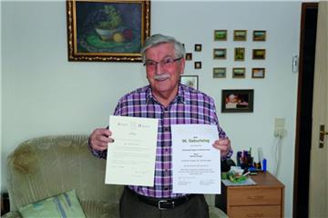 Ein 90. Geburtstag, zwei Glückwünsche: Helmut Krüger hält die Urkunden von der Stadt Hagen in Nordrhein-Westfalen und von der Gemeinde Hagen im Bremischen in der Hand.