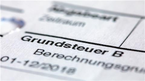 Ein Abgabenbescheid für die Entrichtung der Grundsteuer liegt auf einem Schreibtisch.