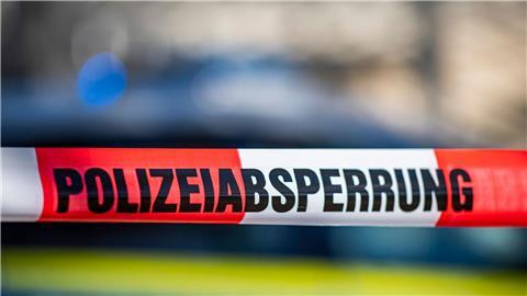 Ein Absperrband der Polizei ist vor einem Streifenwagen aufgespannt.