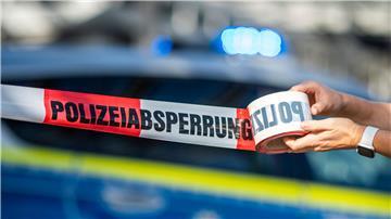 Ein Absperrband wird vor einem Polizeiwagen ausgerollt.