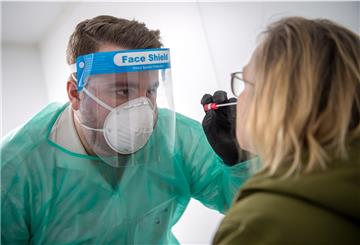 Ein Abstrich für einen PCR-Test wird von einem Mitarbeiter im Corona-Testzentrum genommen.
