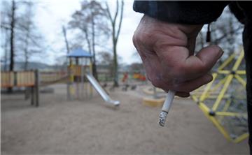 Ein Mann hält auf einem Spielplatz eine Zigarette in der Hand.