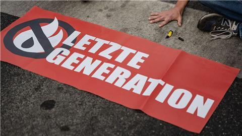 Ein Aktivist der Gruppe „Letzte Generation“ blockiert eine Kreuzung.
