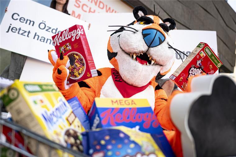 Ein Aktivist in einem Tiger Kostüm sitzt auf einer Demonstration zum "Kinder-Überzuckerungstag" von foodwatch vor dem Landwirtschaftsministerium mit zwei Packungen Frühstücksflocken. 