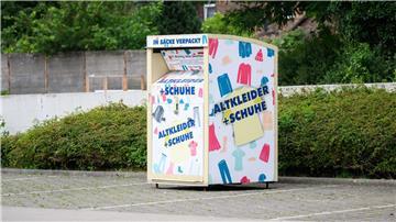 Ein Altkleidercontainer steht auf einem Supermarkt-Parkplatz.