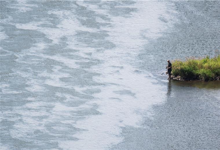 Ein Angler steht an der Weser.