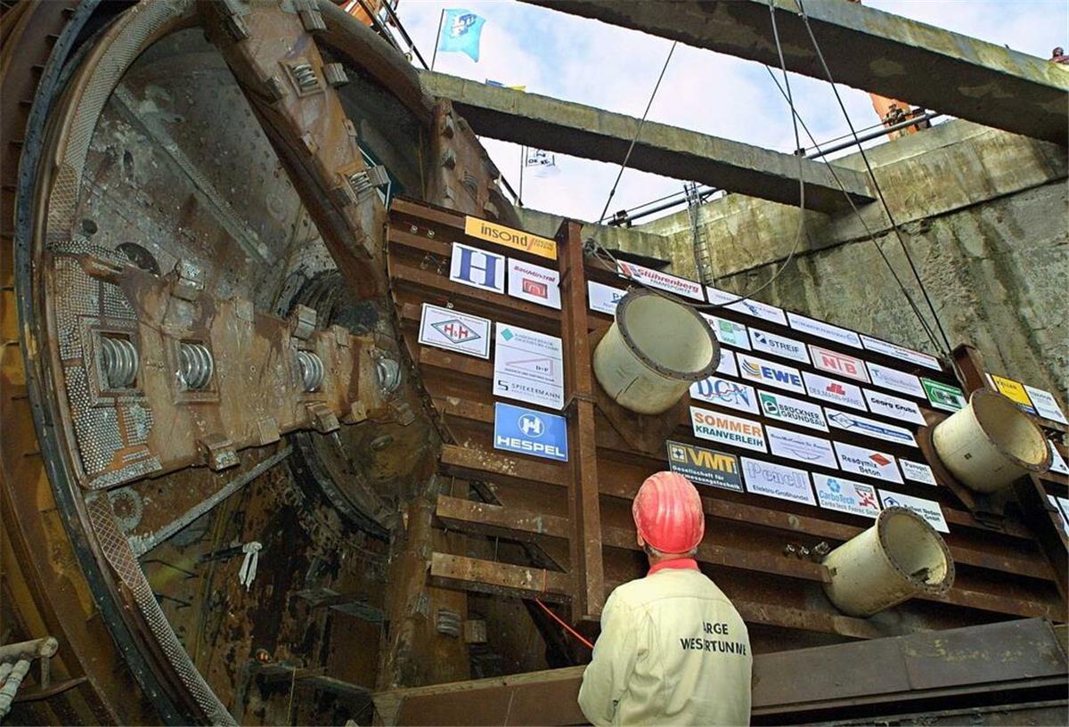 Wesertunnel: Ein Jahrhundertbauwerk feiert runden Geburtstag Ein Arbeiter dirigiert am 7. November 2001 während der Durchstichfeier der zweiten Röhre die Demontage des sogenannten Zieltopfdeckels.
