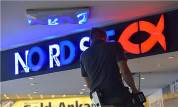 Ein Arbeiter montiert das Logo der Fisch-Restaurantkette "Nordsee" über einem Ladengeschäft in einer Fußgängerzone. 
