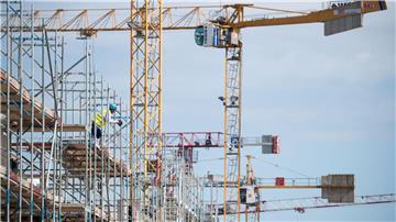 Ein Arbeiter steht auf einer Baustelle für Mehrfamilienhäuser auf einem Gerüst.